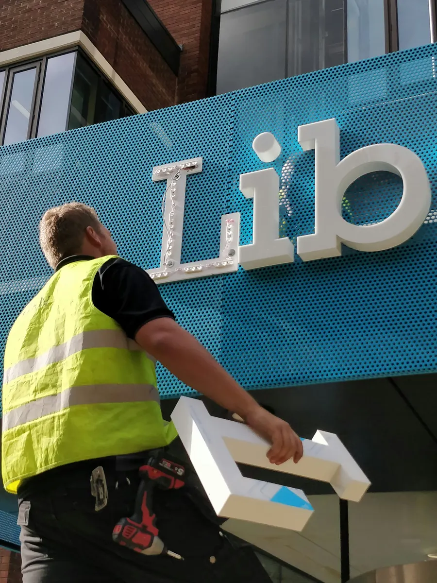Sign installer fitting commercial signage at a customer property