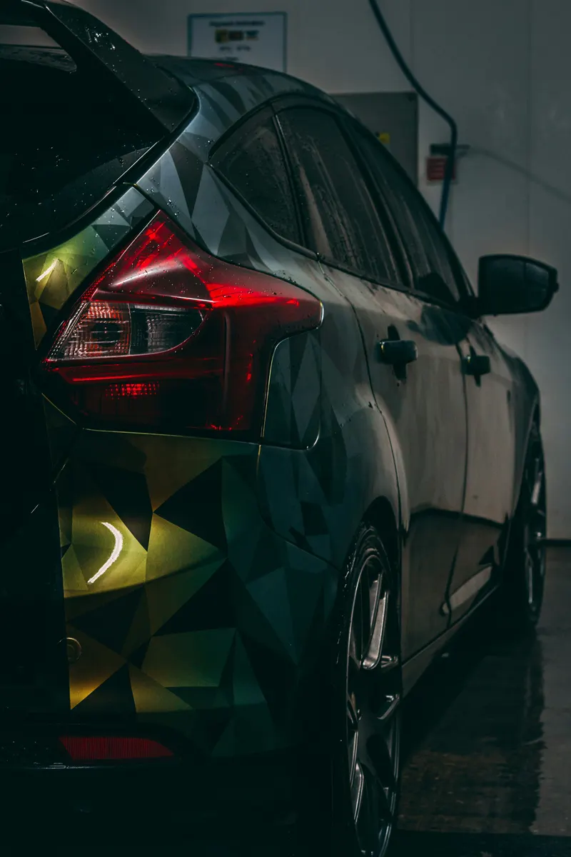 Car wrap installer applying vinyl during a professional vehicle wrapping job
